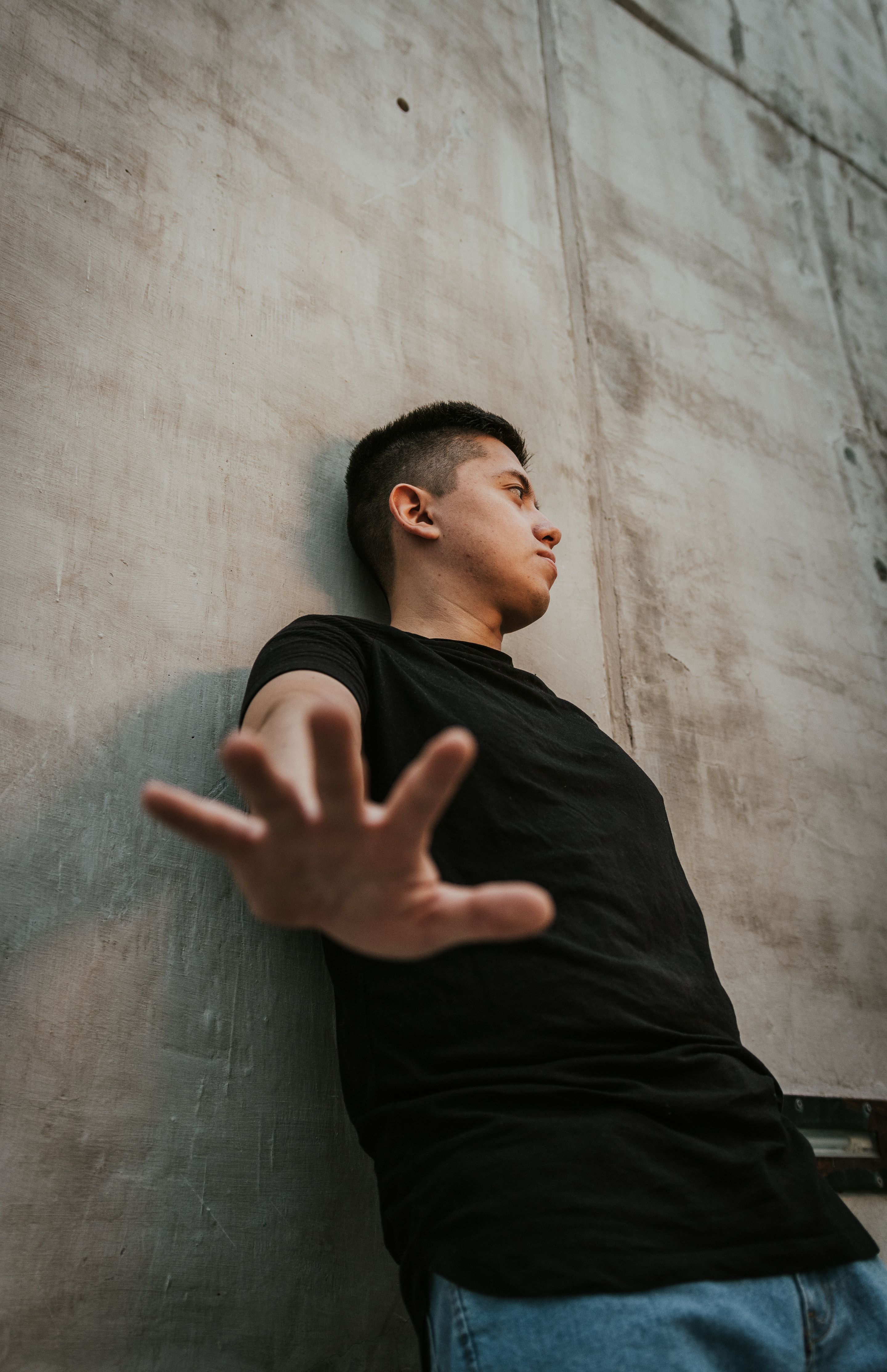 MIKEGAUZZE reaching toward the camera against concrete